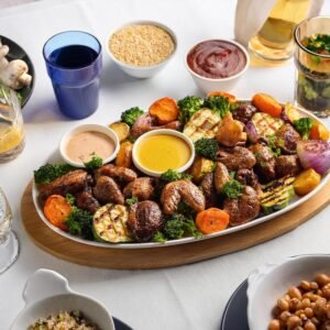 A family-style dinner table featuring chicken hearts, roasted vegetables, and side dishes