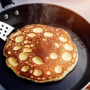 Pancakes cooking on a non-stick griddle with bubbles forming on the surface