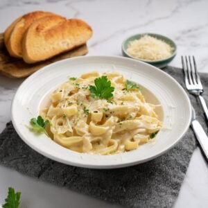 A bowl of creamy Alfredo pasta garnished with parsley and Parmesan cheese