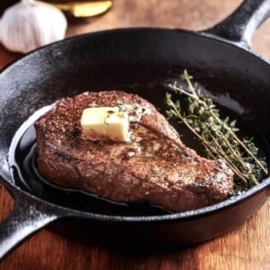 Chuck eye steak being seared in a cast-iron skillet