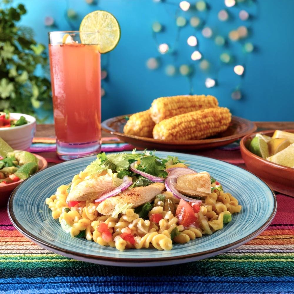 A colorful bowl of Mexican salad with fresh lettuce, tomatoes, avocado, corn, and beans