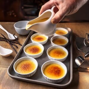 A creamy custard base of crème brûlée being poured into ramekins.