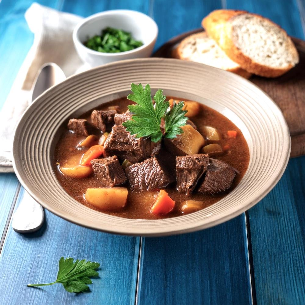 A serving of beef stew with crusty bread on the side.