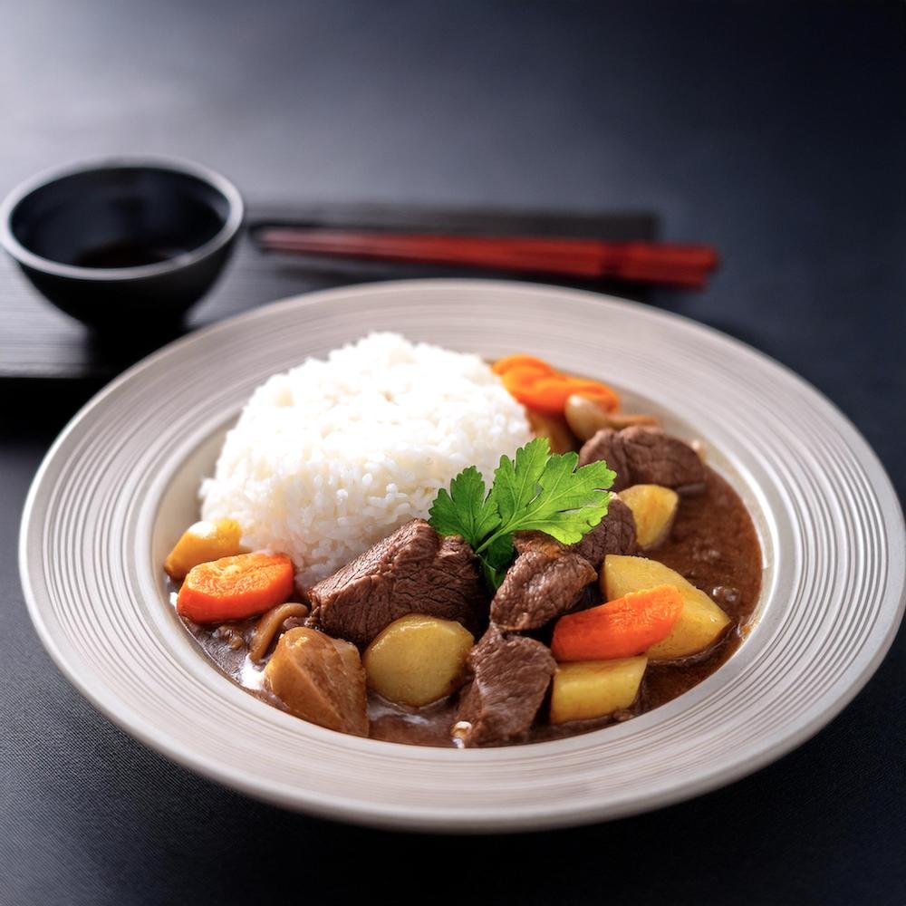 Japanese beef stew served over steamed white rice in a shallow bowl