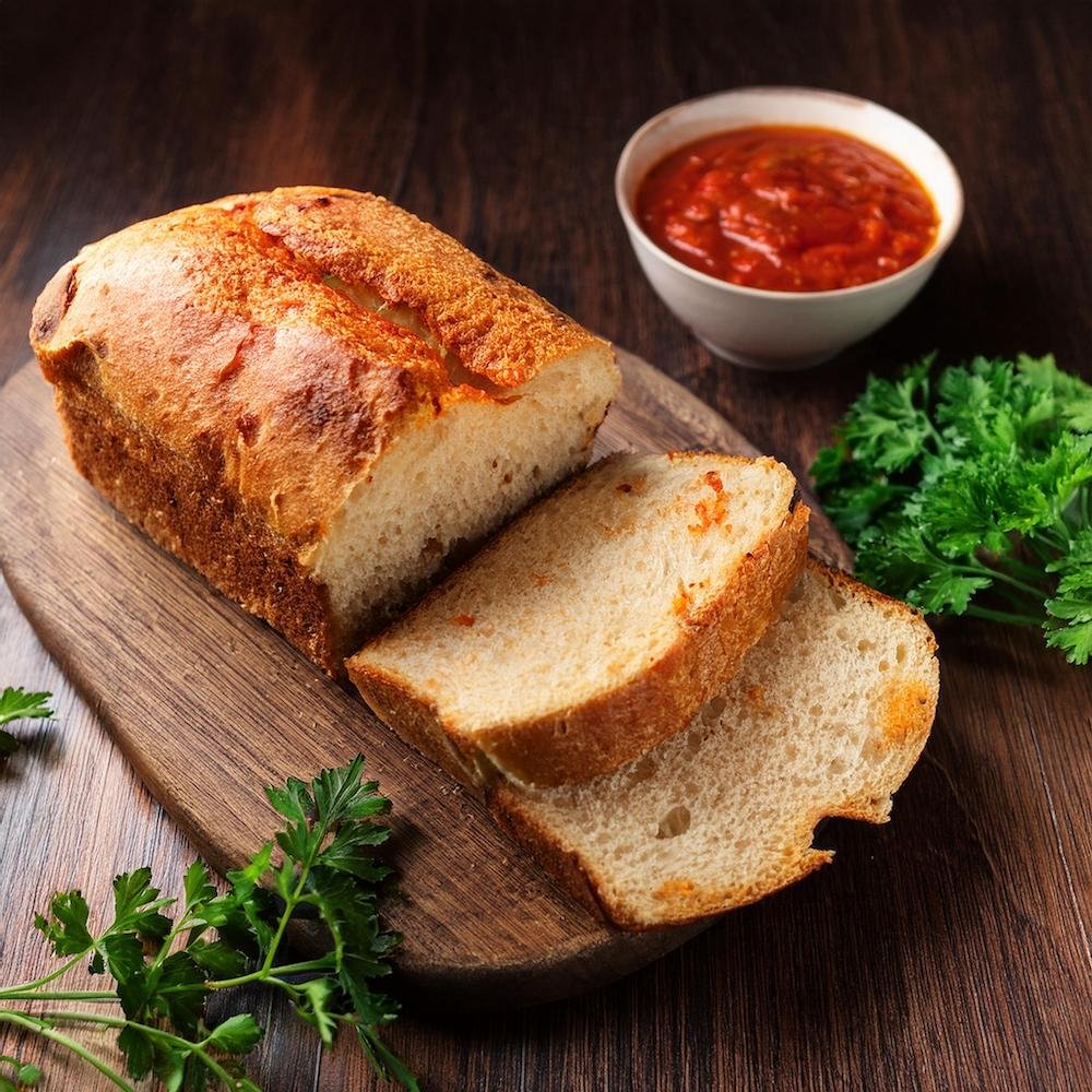 A freshly baked garbage bread loaf sliced to reveal cheese, pepperoni, and sauce filling