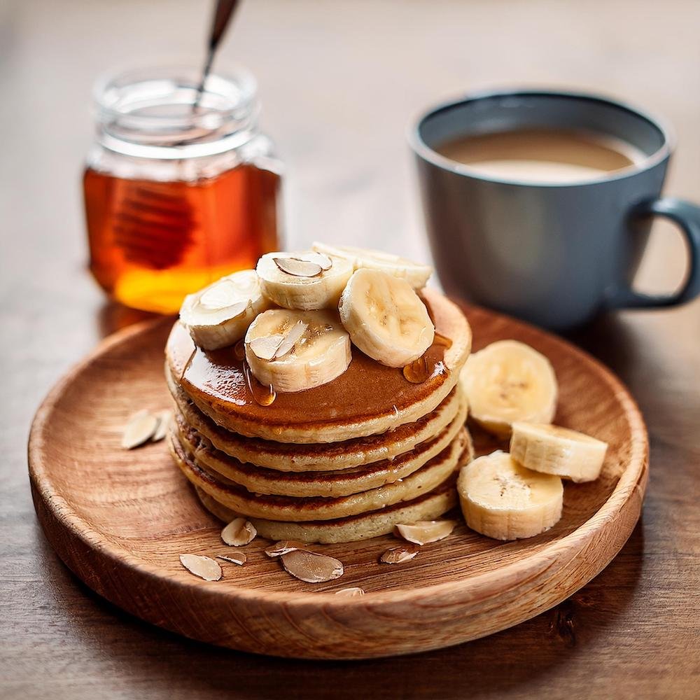 A plate of whole wheat pancakes topped with almond butter and banana slices.