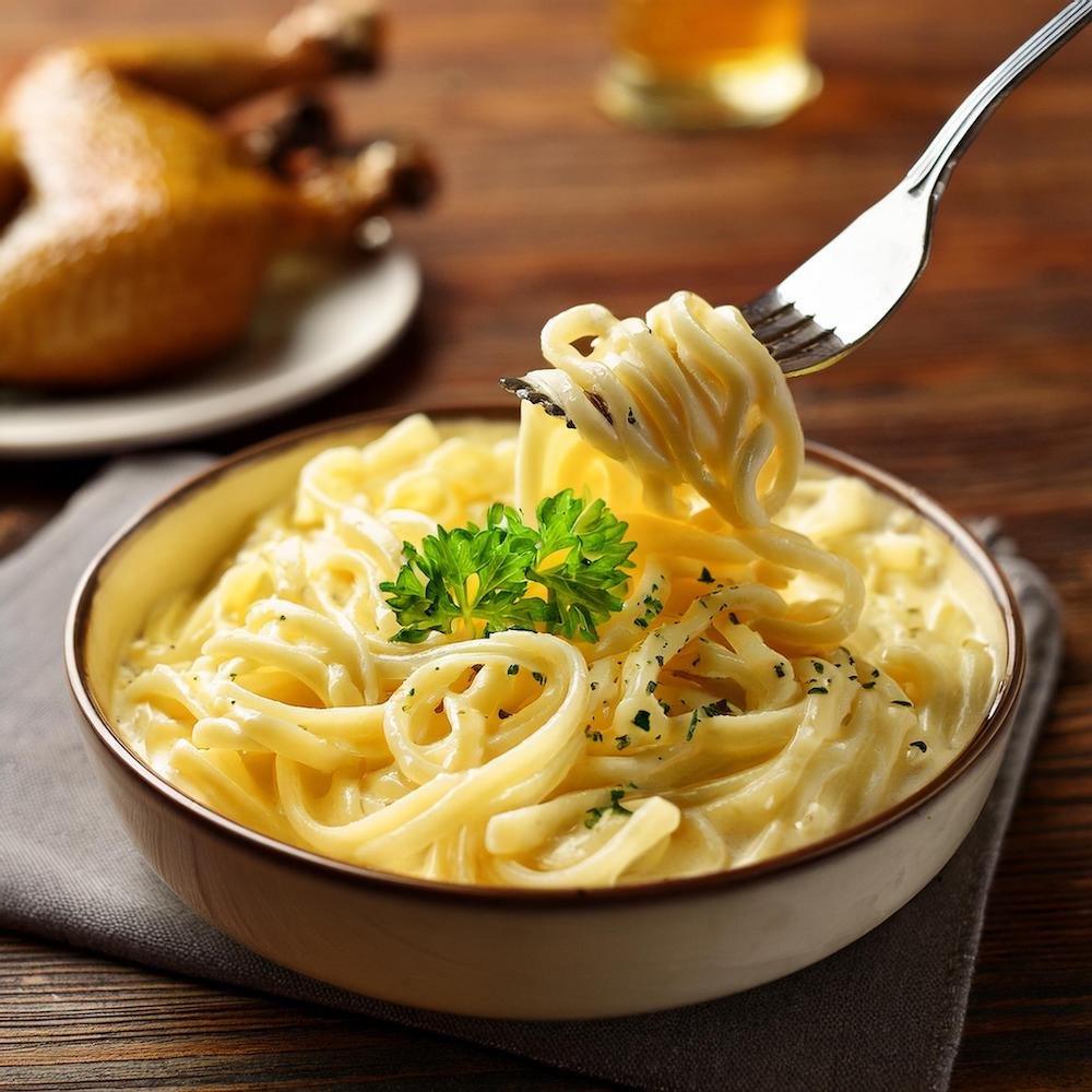 A bowl of creamy cafeteria noodles with parsley garnish