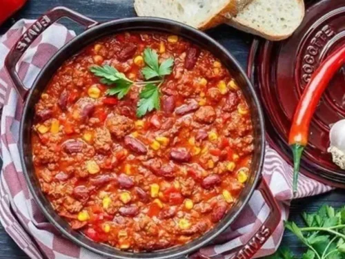 Delicious bowl of Chili with Meat topped with fresh herbs and served in a rustic dish.