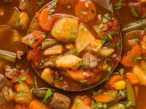 Bowl of hearty Crockpot Vegetable Beef Soup with fresh vegetables