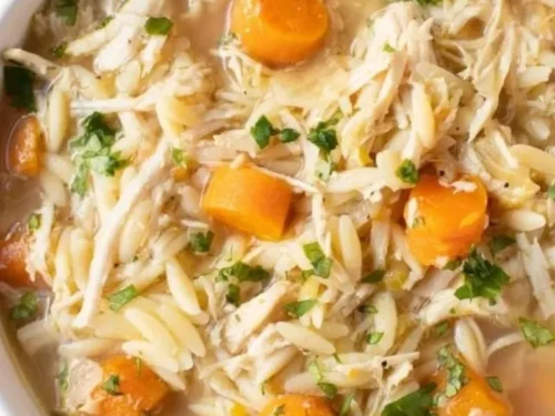 Bowl of Greek Lemon Chicken Soup with lemon slices and fresh herbs.