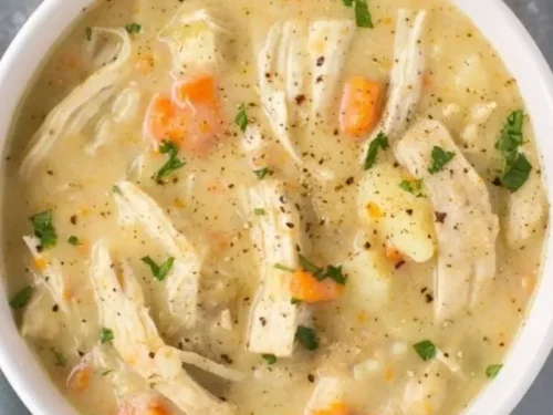 Bowl of healthy chicken pot pie soup with fresh vegetables and herbs.