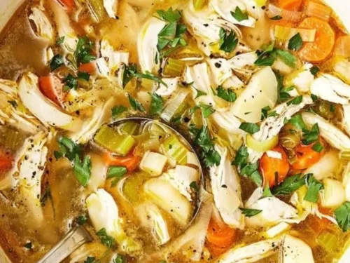 Bowl of homemade chicken soup with vegetables and herbs