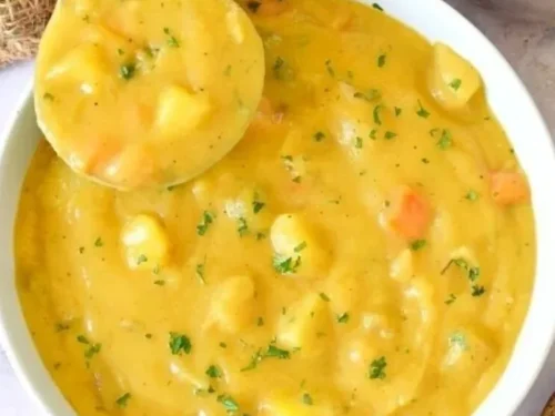 Bowl of homemade German potato soup garnished with herbs and spices