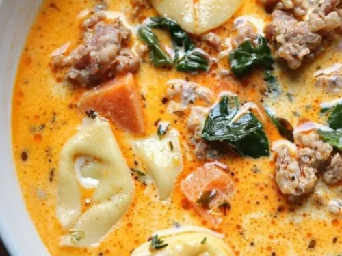 Bowl of Sausage Tortellini Soup with Spinach garnished with herbs