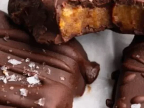 Four ingredient date caramels on a wooden plate with nuts and cocoa.