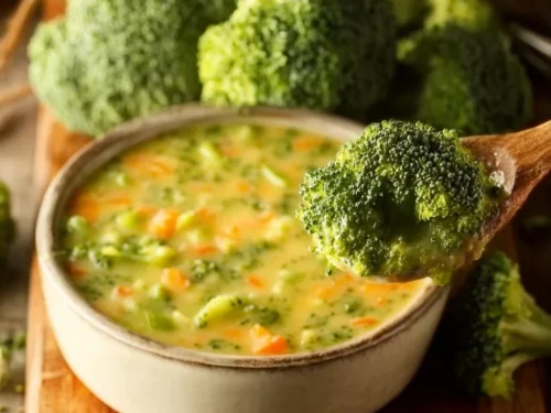 Bowl of creamy broccoli cheddar soup garnished with fresh herbs