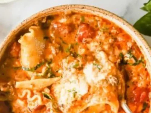 Creamy lasagna soup served in a bowl with fresh herbs and cheese on top.