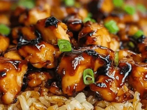 Delicious honey BBQ chicken served over rice, garnished with fresh herbs.