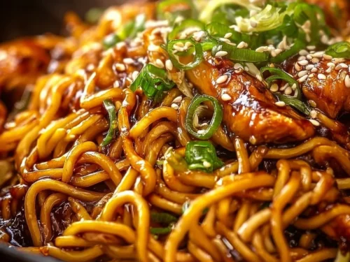 Delicious sticky garlic chicken noodles in a bowl with green onions
