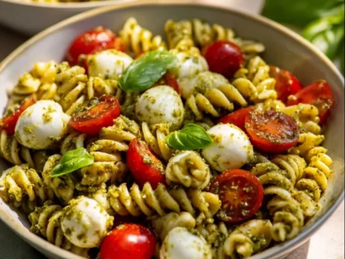 Bowl of Pesto Caprese Pasta Salad with fresh basil and cherry tomatoes